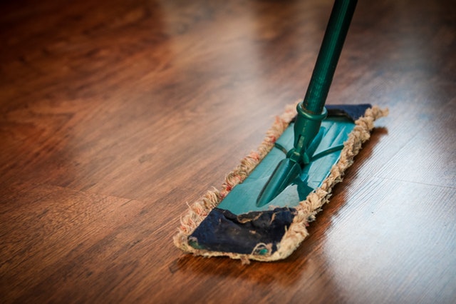 A mop in green color image cleaning a floor tile